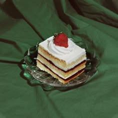 a piece of cake sitting on top of a glass plate with a strawberry on top