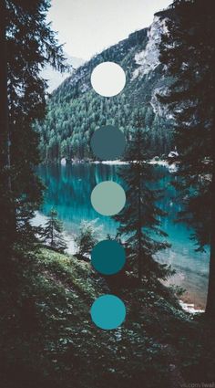 a lake surrounded by trees and mountains with circles in the sky above it that are floating on water