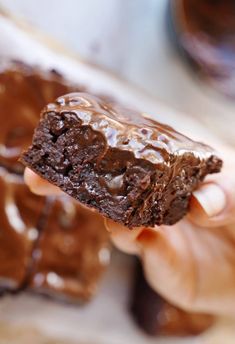 a person holding up a chocolate brownie in their hand