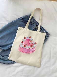 a tote bag sitting on top of a bed next to a pair of jeans