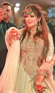 a woman in a bridal outfit is walking down the aisle with her hand on her hip