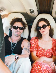 a man and woman sitting in the back of an airplane with sunglasses on their heads