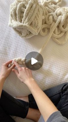 a woman is laying on the bed with her feet up next to a pile of yarn