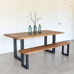 a wooden table with two vases on it and a bench in front of it