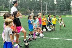 a group of young children standing on top of a soccer field next to each other