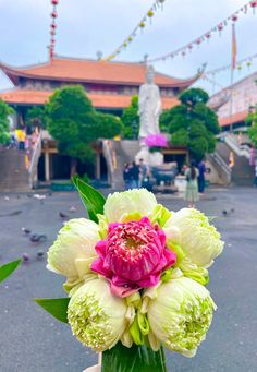 a vase filled with white and pink flowers on top of a table next to a building