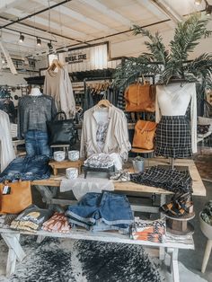 clothes and handbags are on display in the store's clothing section, while other items sit on tables