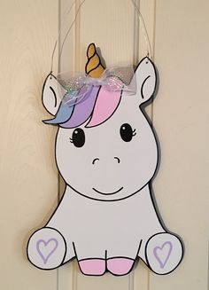 a wooden unicorn decoration hanging on a door with a bow around it's head