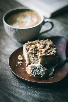 a piece of cake sitting on top of a wooden plate next to a cup of coffee