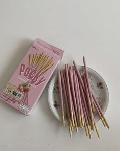 there are many pink sticks on the plate next to some tea bags and a box