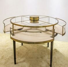 a round glass table with metal legs on carpeted floor