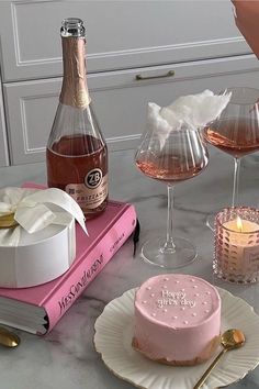 a table topped with cakes and wine glasses filled with pink liquid next to a cake