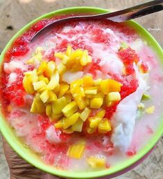 a person holding a bowl of fruit and yogurt with a spoon in it