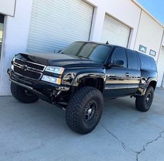 a large black truck parked in front of a garage