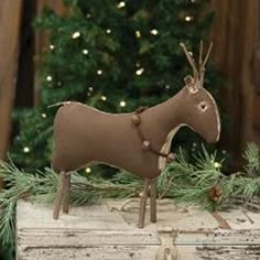 The Stiffened Standing Reindeer is a decorative primitive plush reindeer figurine made of stiffened fabric with a rustic brown finish. The reindeer has bead eyes, twig legs and antlers, and wears a brown wreath collar with rusted jingle bells. Display this reindeer standing on a shelf or tabletop to bring a primitive country touch to the home during the Christmas season. Measures 10” high by 10” wide by 3” deep. Brown Wreath, Primitive Christmas Crafts, Primitive Ornaments, Reindeer Figure, Primitive Christmas Decor, Wood Ceiling Lights, Primitive Wood Signs, Primitive Candles, Flameless Tea Lights