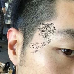 a close up of a person with a tattoo on their forehead and behind his ear