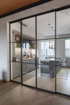 an open glass door leading to a dining room and living room area with white walls