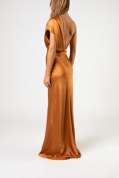 the back of a woman in an orange dress, looking down at her left shoulder