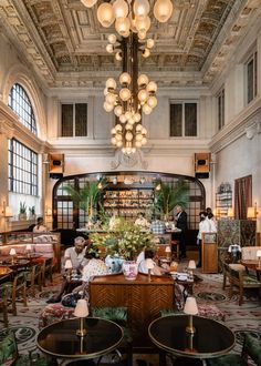 the interior of a restaurant with chandeliers hanging from the ceiling and people sitting at tables