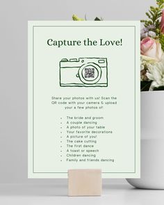 a white vase filled with flowers next to a green sign that says capture the love