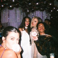 four women pose for a photo in front of balloons