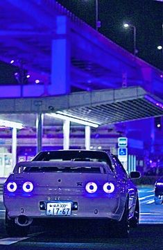 a car parked in front of a parking garage with purple lights on it's windows