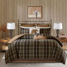 a bed with plaid comforter and pillows in a room next to two lamps on either side of the bed