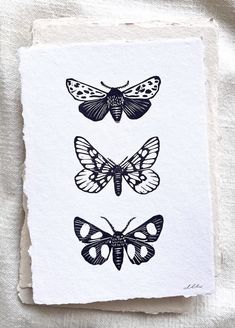 three butterflies are shown on top of a piece of white paper, with black ink