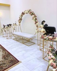 a room filled with lots of white and pink flowers next to gold stands on top of marble flooring