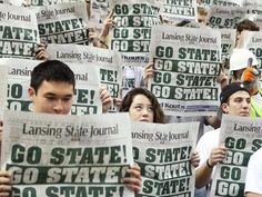 a group of people holding up newspapers with the words go state on them in front of them