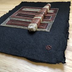 a piece of black wool with red, white and blue designs on it sitting on top of a wooden floor