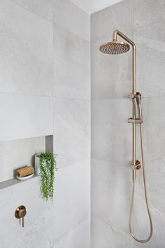 a shower head and thermostaer in a white tiled bathroom with gold faucet