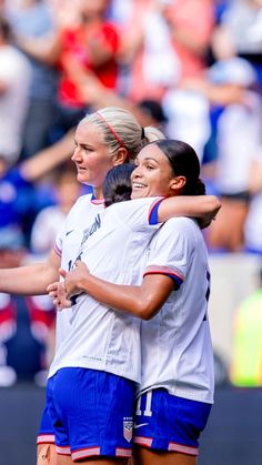 two female soccer players hugging each other on the field