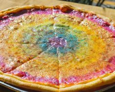 a rainbow colored pie sitting on top of a wooden table