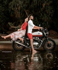 a man and woman riding on the back of a motorcycle in the middle of water