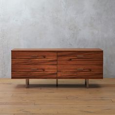 a wooden dresser sitting on top of a hard wood floor next to a white wall