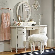 a white vanity with a mirror, stool and other items on the table in front of it