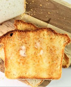 two pieces of bread sitting on top of a cutting board next to a slice of bread