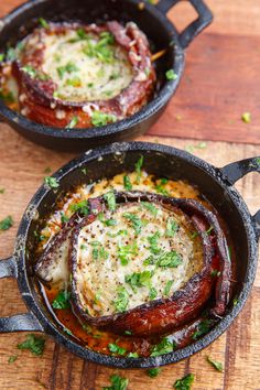 two cast iron pans filled with food on top of a wooden table