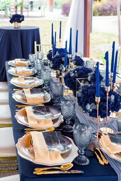 a table set with blue and gold place settings