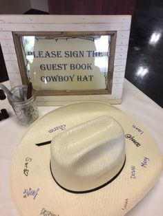 a cowboy hat sits next to a sign that reads please sign the guest book cowboy hat