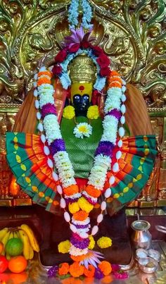 there is a statue with flowers on it and fruit in the foreground, along with other decorations