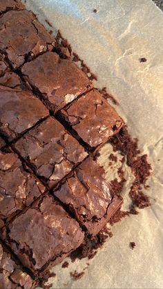 a piece of chocolate brownie sitting on top of parchment paper