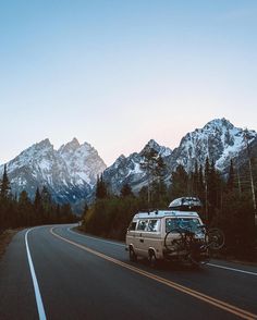 the van is parked on the side of the road in front of some mountain peaks