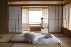 a person sitting on top of a bed in a room with tatami mats and pillows