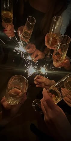 people holding wine glasses with sparklers in them