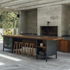 an outdoor kitchen with bar stools next to the counter and oven in the background