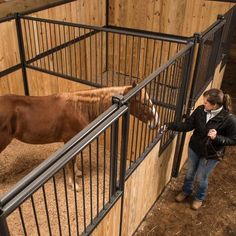 a woman standing next to a brown horse in a pen