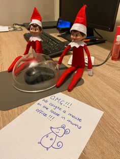 two elfs sitting on top of a desk next to a computer keyboard and mouse