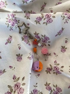 the fabric is covered with pink and orange flowers, beads, and an animal keychain